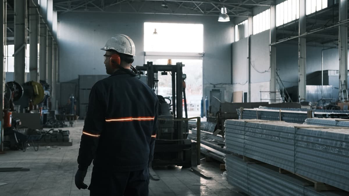 Operador con casco y protección auditiva caminando por una nave industrial